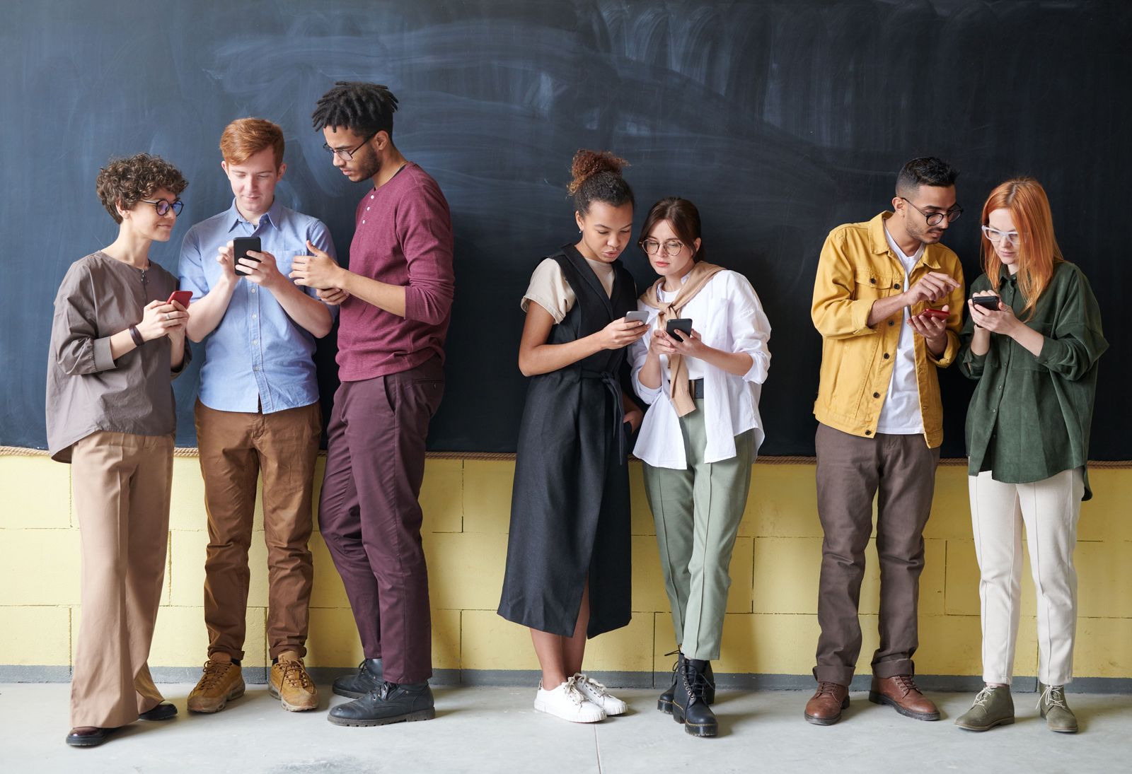 A group of friends standing in a row, each paying on their phone